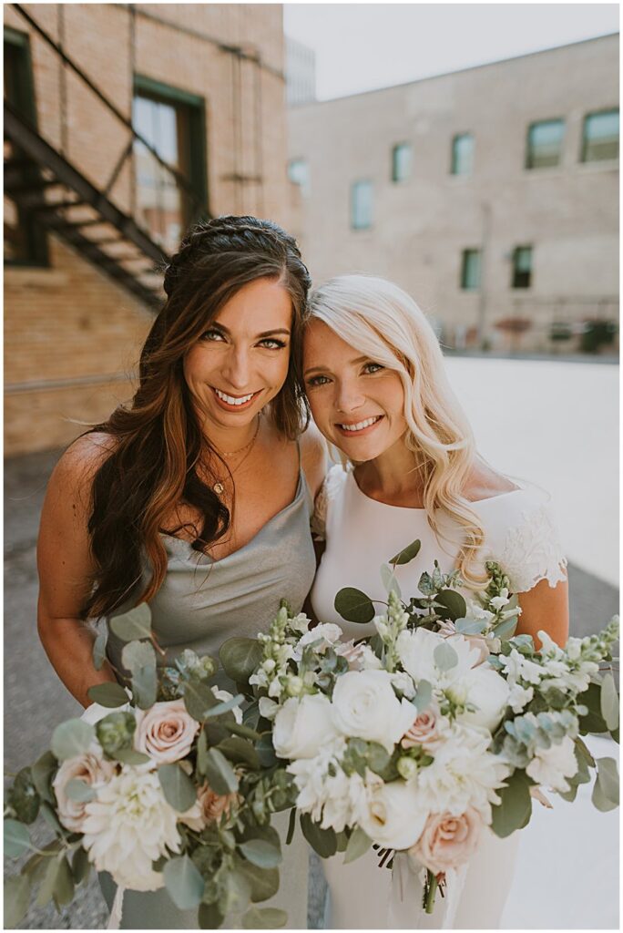 bride with bridesmaid holding wedding florals